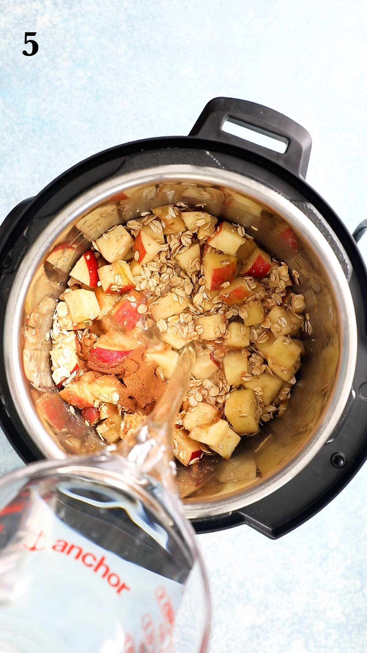 Pouring water into an instant pot with chopped apples and oats.