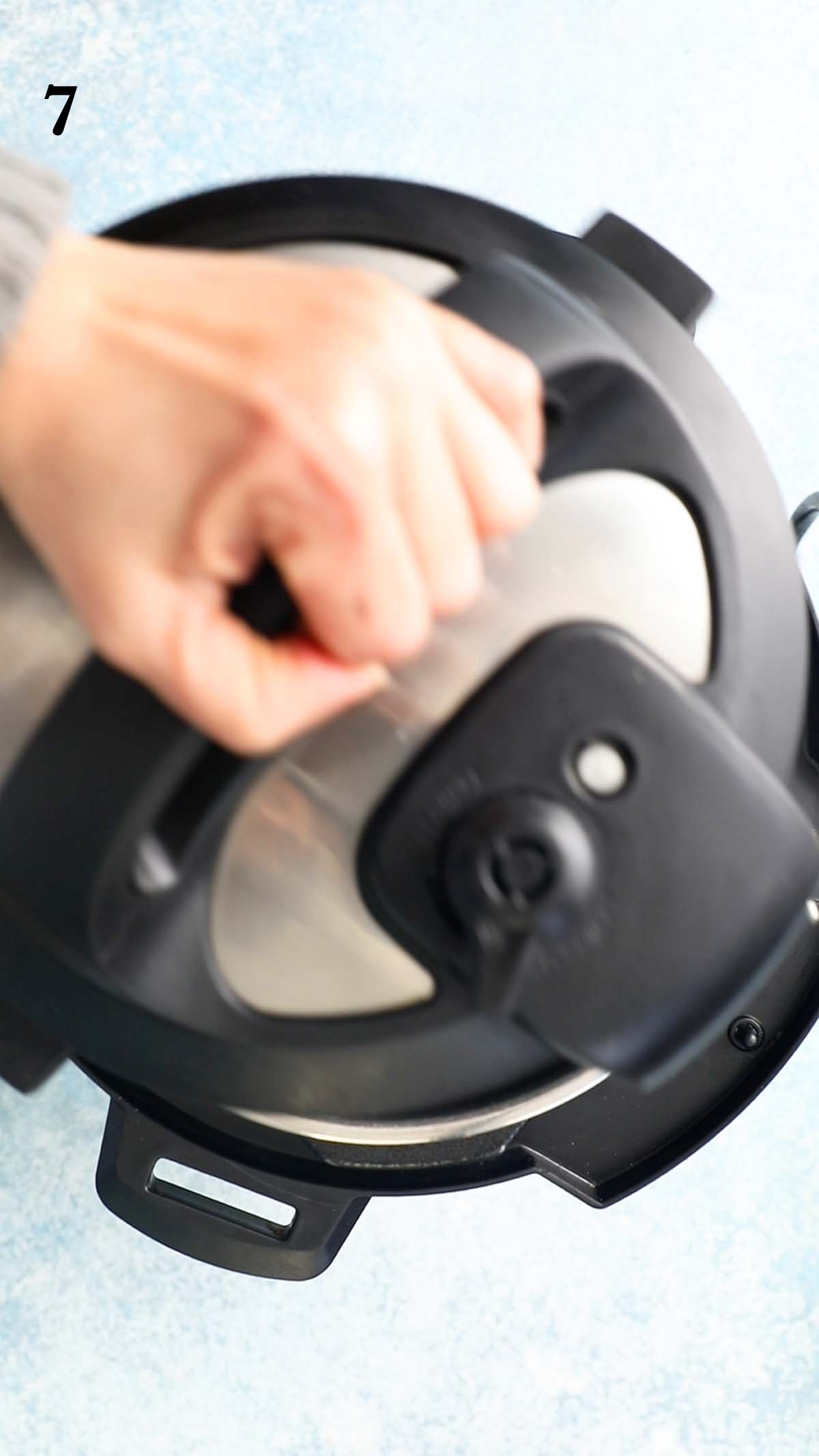 a hand closing an instant pot with a lid.