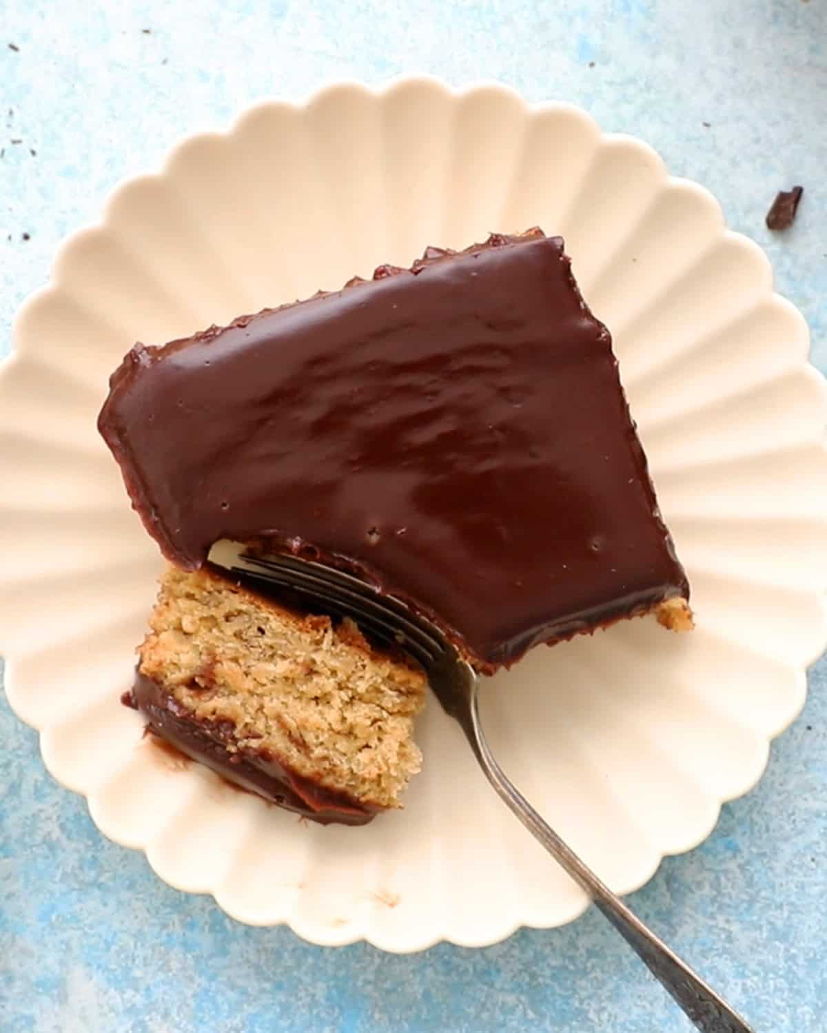 one square slice of banana cake in a white plate along with a fork.