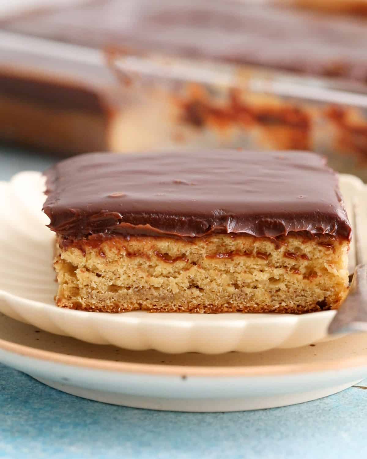 one square slice of banana cake in a white plate along with a fork.