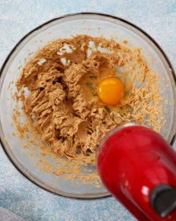 brown sugar and egg in a glass bowl along with a red beater.