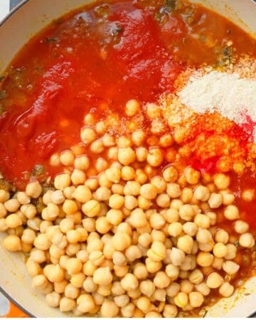 cooked chickpeas and red tomato sauce in a white pan.