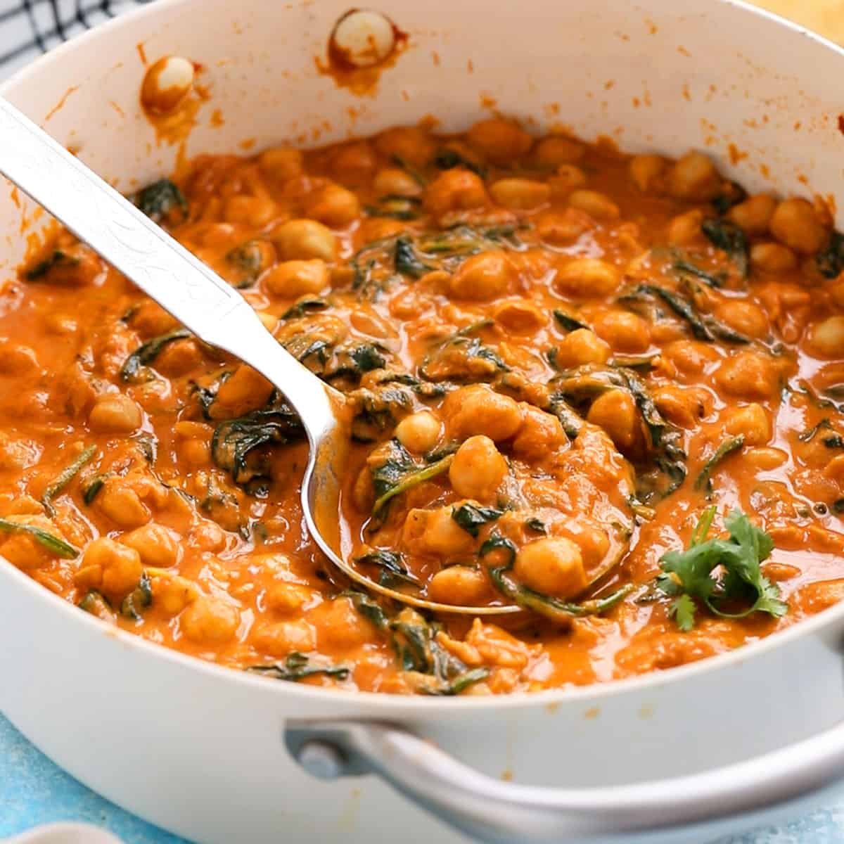 chickpea and spinach curry in a white pan.