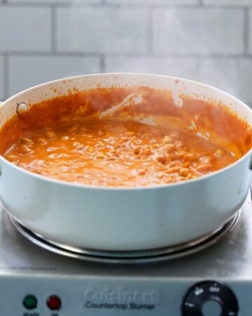 Indian chickpea curry cooking in a white pan.