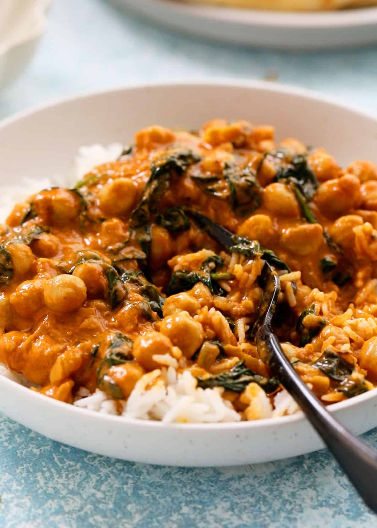 chickpea curry with white rice in a white bowl.