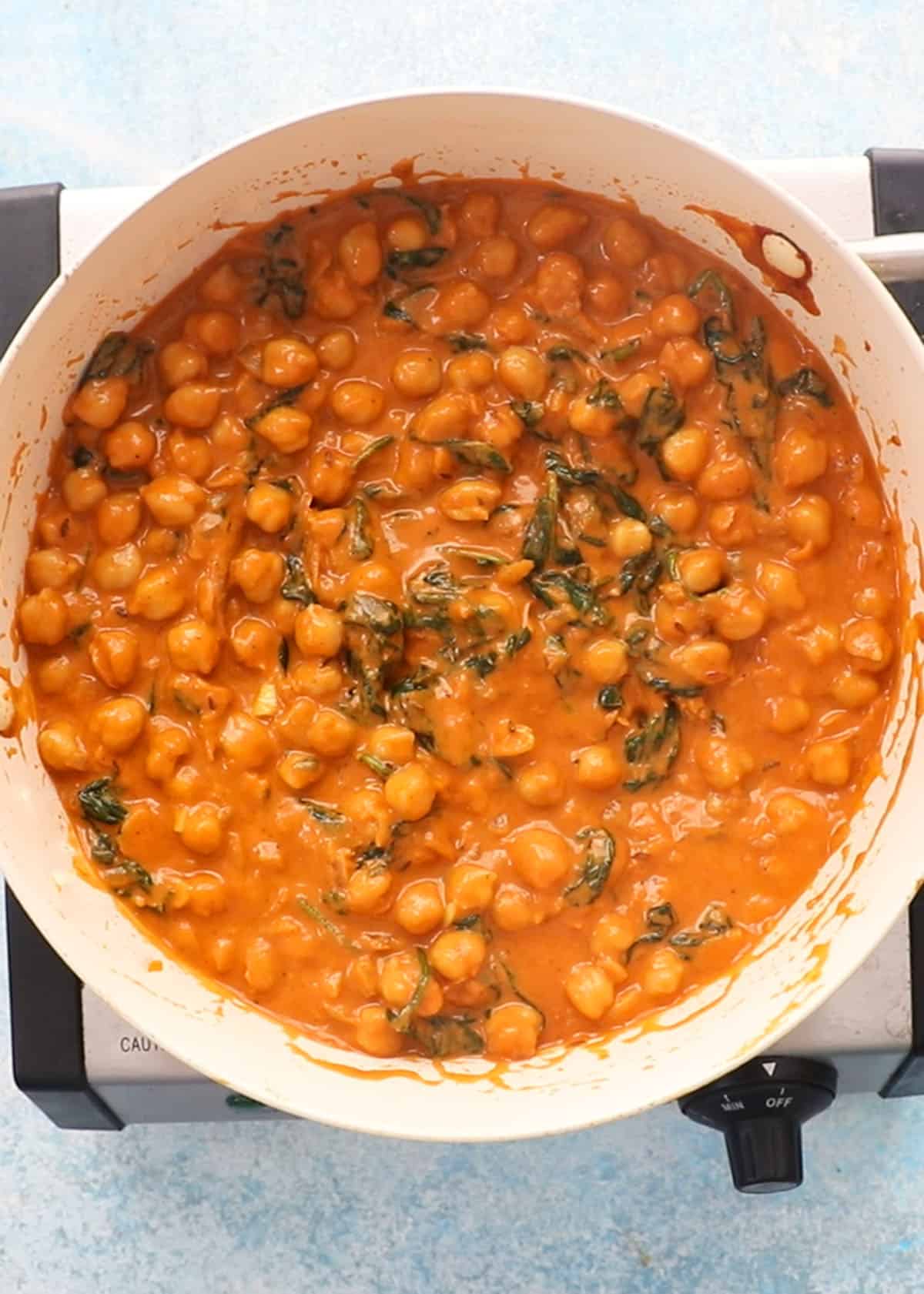 chickpea and spinach curry in a white pan.