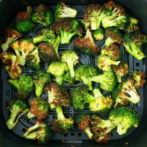 roasted broccoli florets in a black air fryer plate.