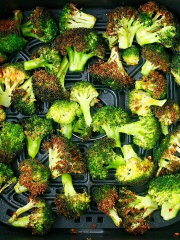 roasted broccoli florets in a black air fryer plate.