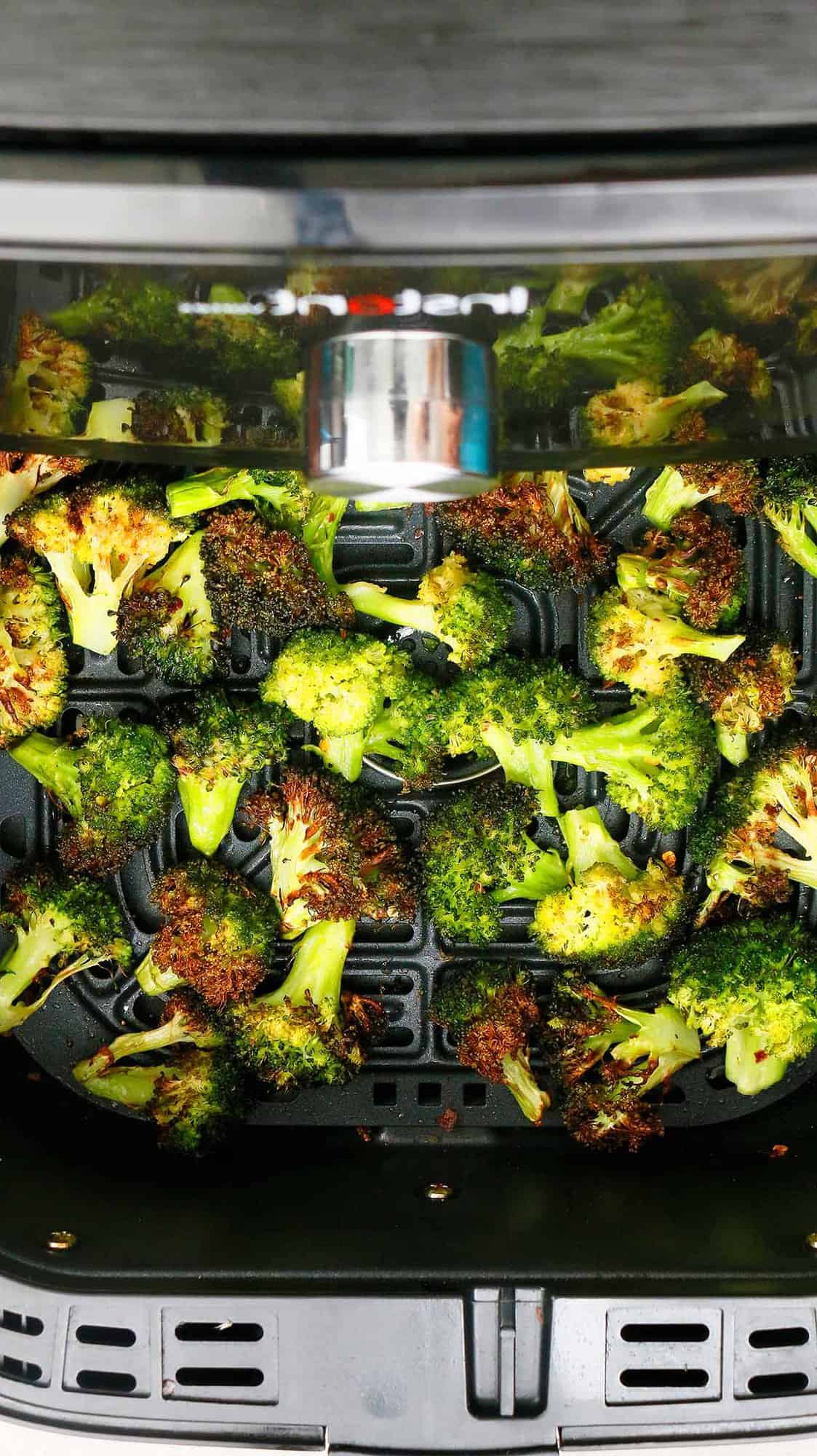 air fryer basket with roasted broccoli.
