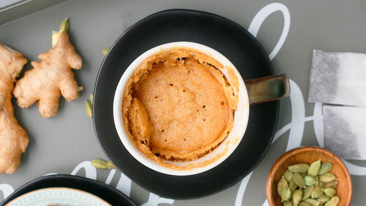 one white mug with cooked chai cake, placed in a black plate.