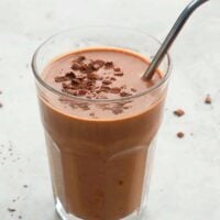 one tall glass with brown smoothie and a stainless steel straw.