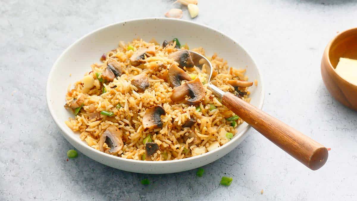 one white bowl with mushroom rice and a wooden spoon.