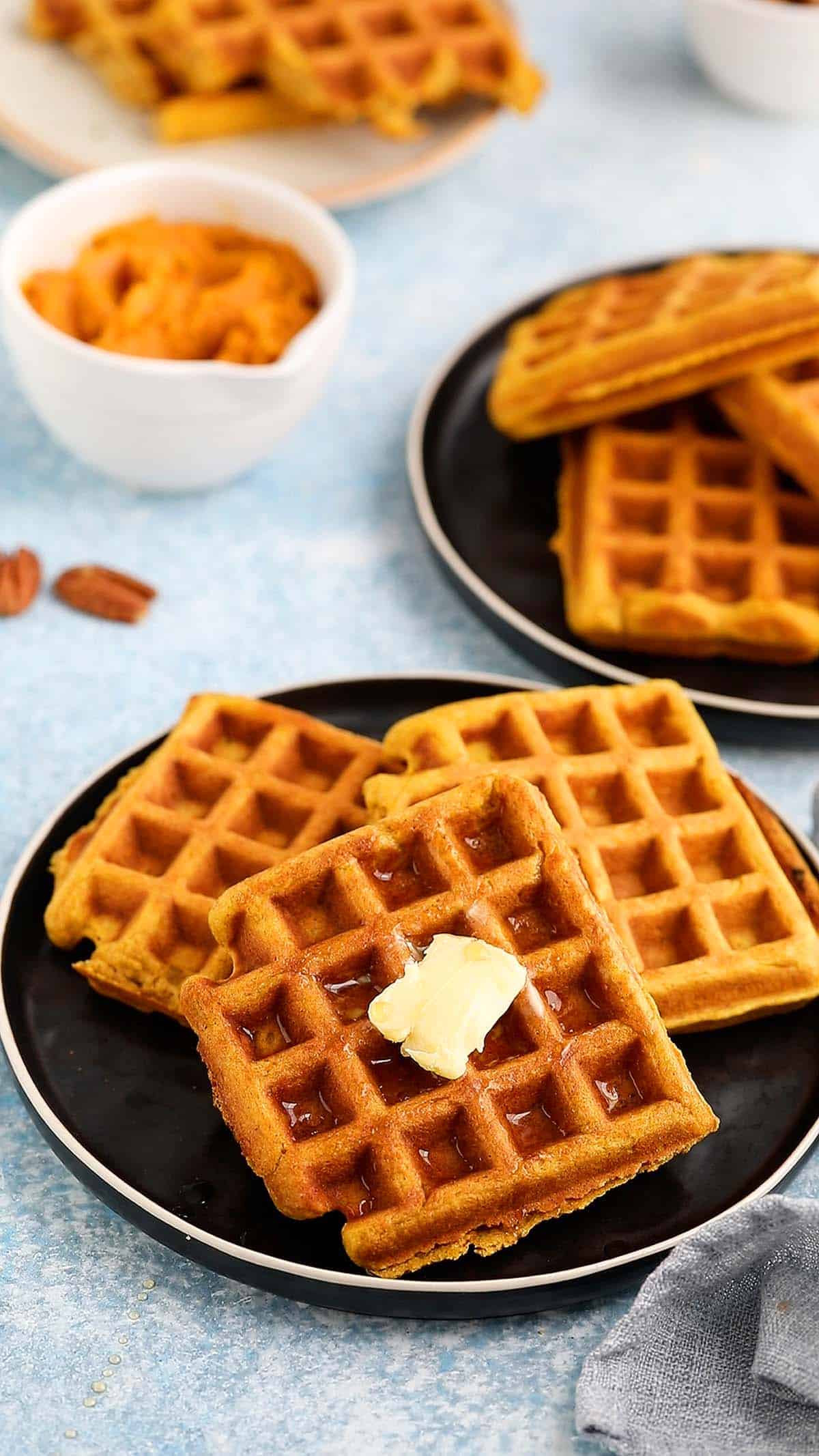 3 plates with cooked waffles topped with syrup.