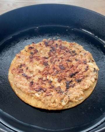 one smashed chicken taco cooking in a black skillet.