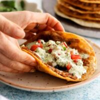 two hands holding one smashed chicken taco.