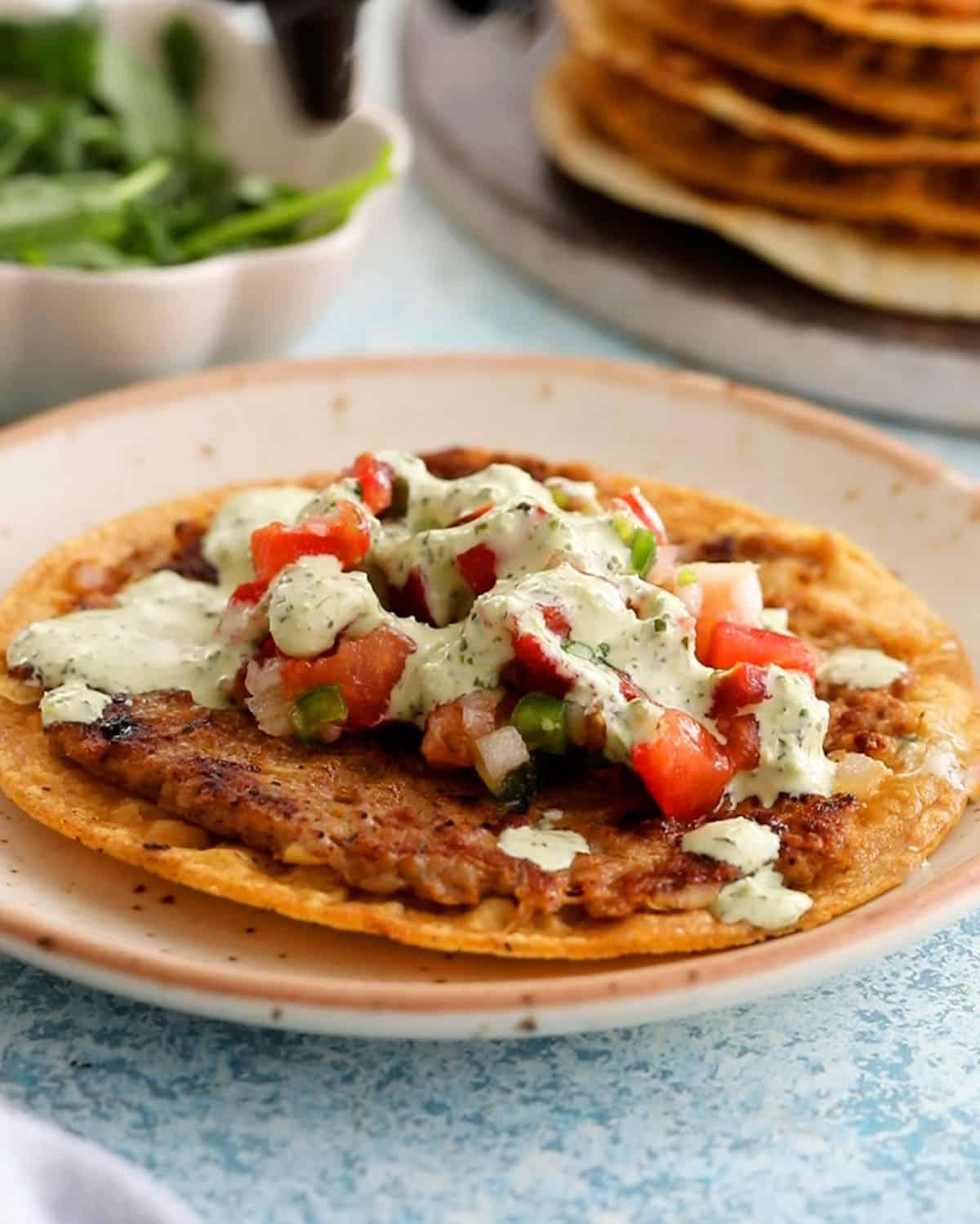 one smashed chicken taco in a white plate.
