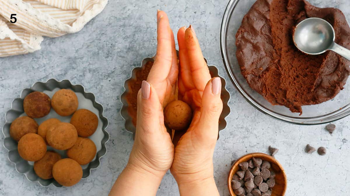2 hands rolling a chocolate truffle. 