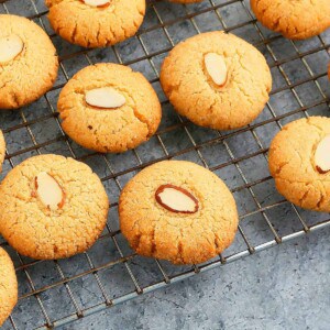 small golden colored almond cookies placed on a wire rack.