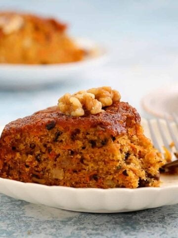 one slice of carrot cake placed in a round white plate.