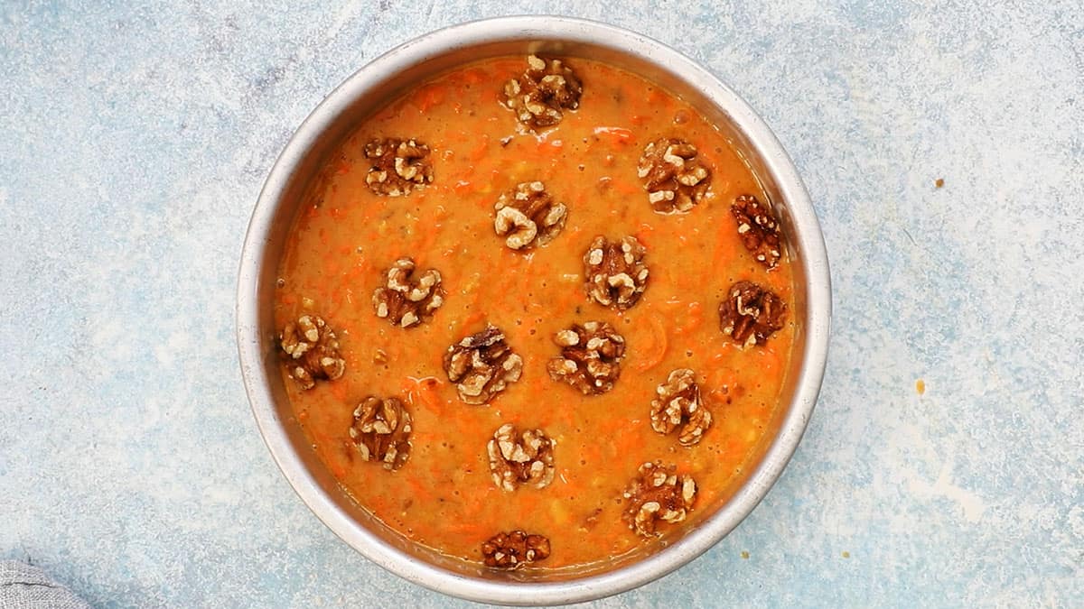 carrot cake batter in a metal round pan. 