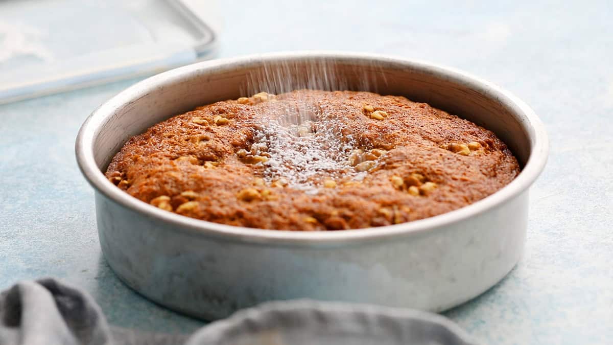 one baked carrot cake in a round metal cake pan.