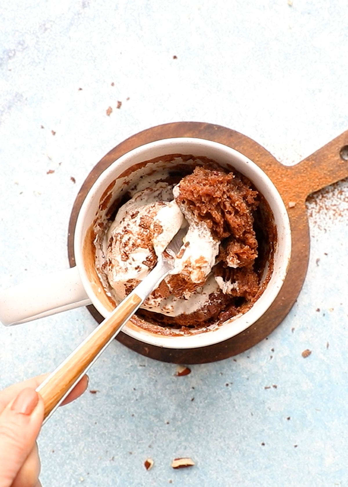 white mug with mocha cake, topped with whipped cream and a spoon.