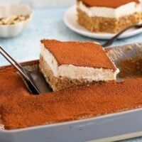 a hand removing one slice of tres leches cake from a baking pan.