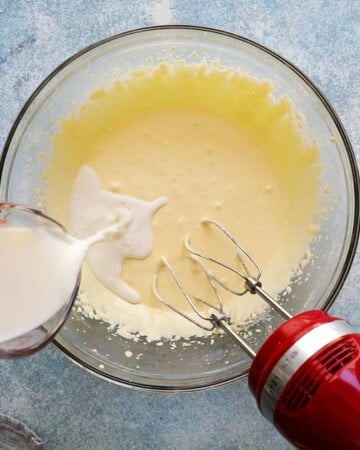 a hand pouring white milk into a large glass bowl.
