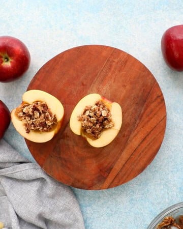 2 stuffed apple halves on a wooden board.
