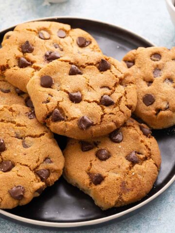 6 chocolate chip cookies on a round black plate.
