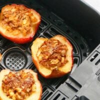3 baked apple halves in an air fryer basket.