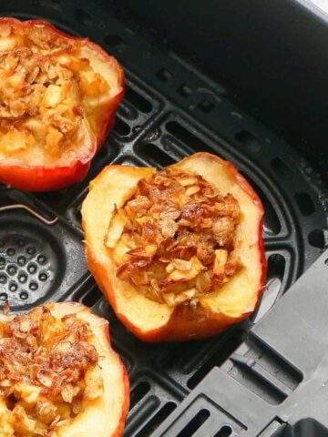 3 baked apple halves in an air fryer basket.