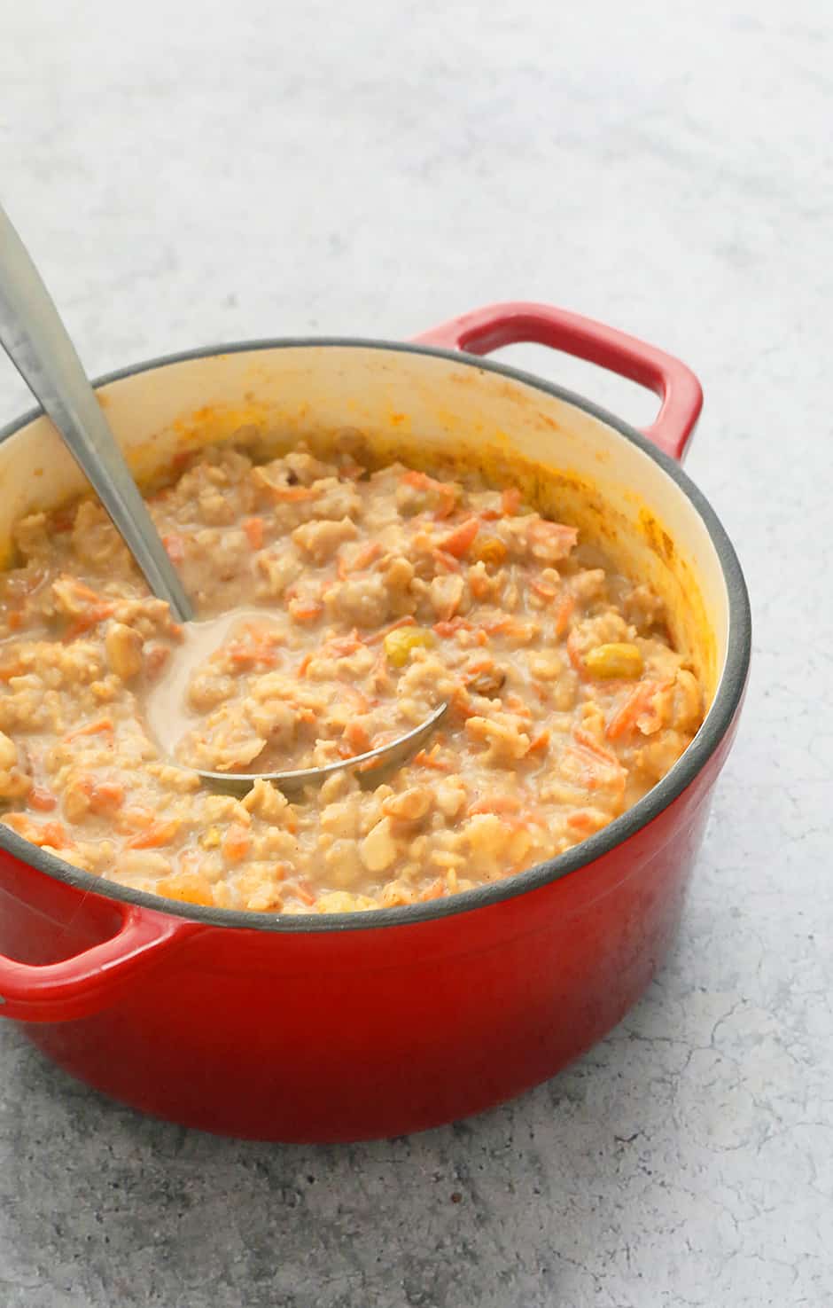 a red enameled cast iron pot with creamy carrot cake oatmeal with a spoon