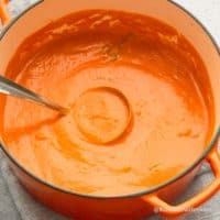 dutch oven with creamy homemade tomato soup along with spatula..