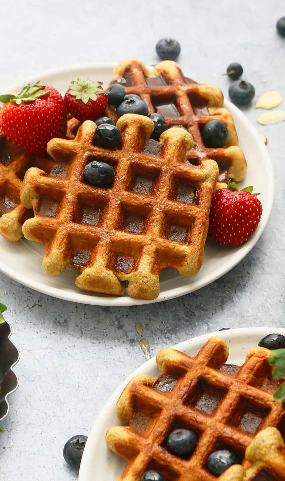 white plates with healthy waffles topped with maple syrup and berries