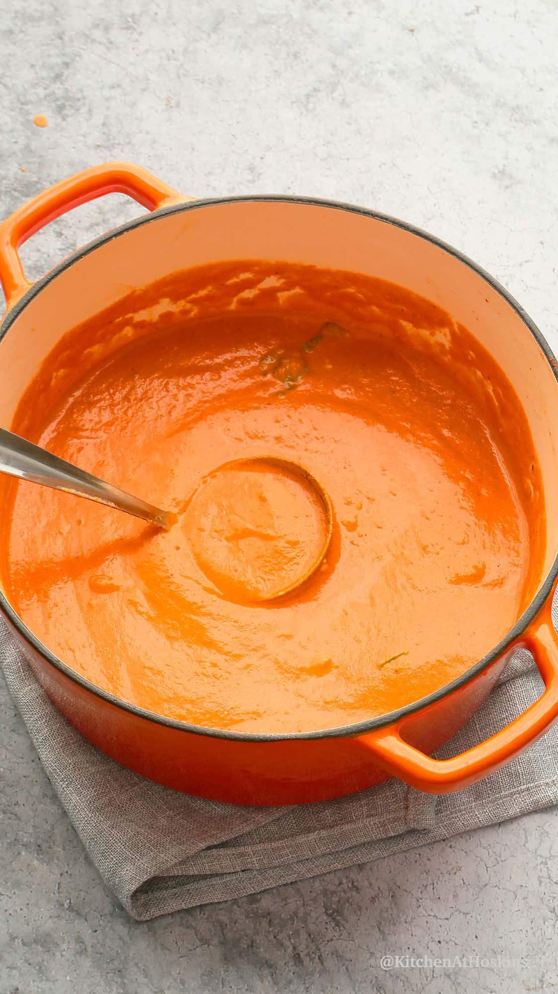 dutch oven with healthy creamy tomato basil soup along with spoon.