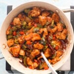 Hunan chicken with vegetables in a white pan.