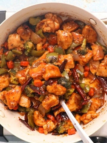Hunan chicken with vegetables in a white pan.