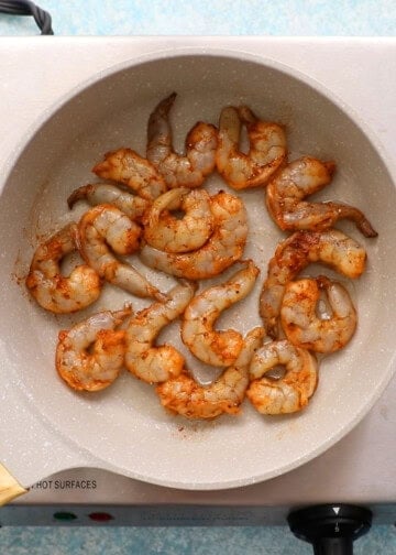 shrimp cooking in a white skillet.