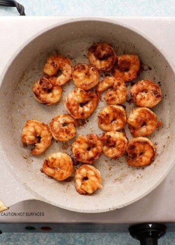 shrimp cooking in a white skillet.