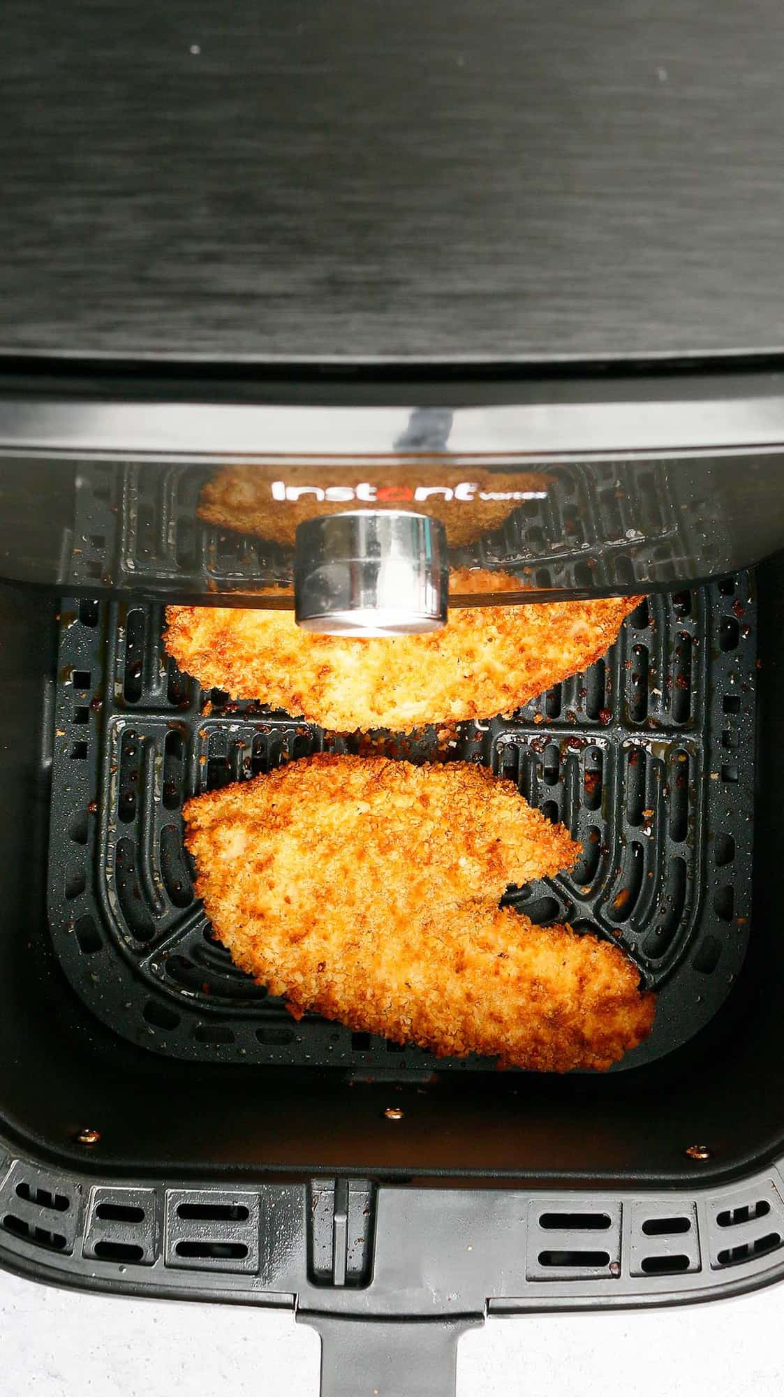an air fryer basket with breaded tilapia 