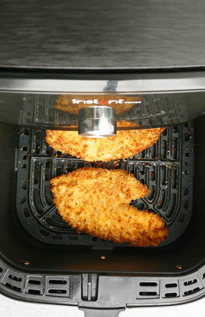 removing the basket from the air fryer with freshly cooked fish