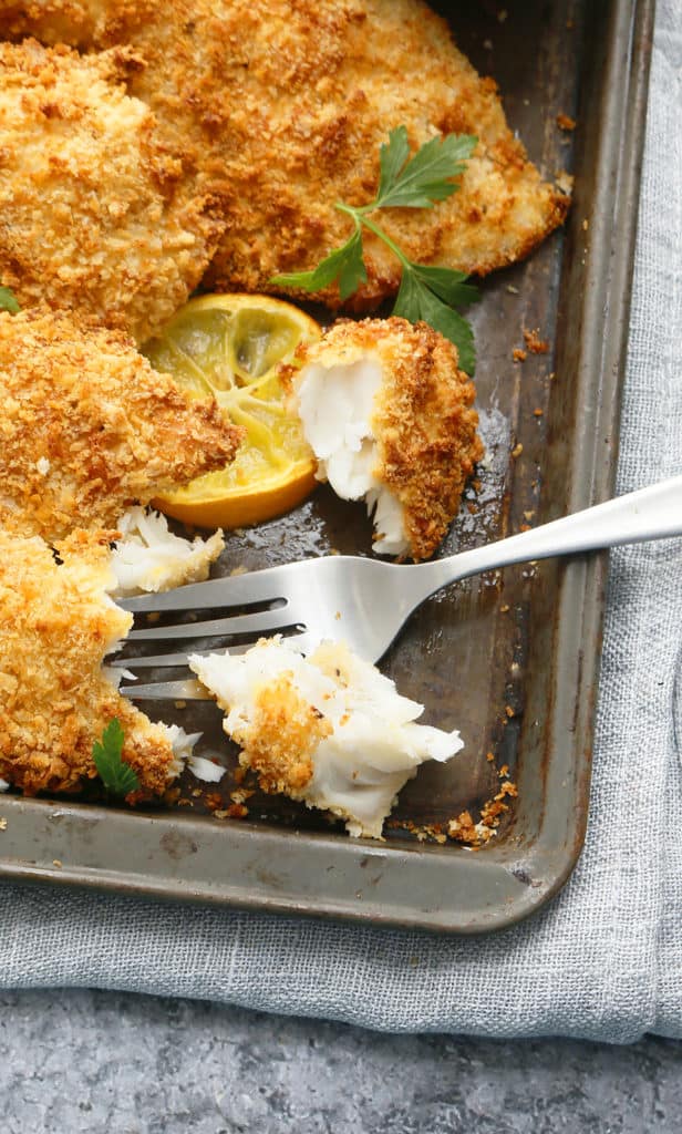 sheet pan with air fryer tilapia with a chunk broken off with a fork