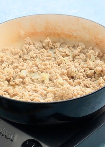 ground chicken meat cooking in a large white pan.