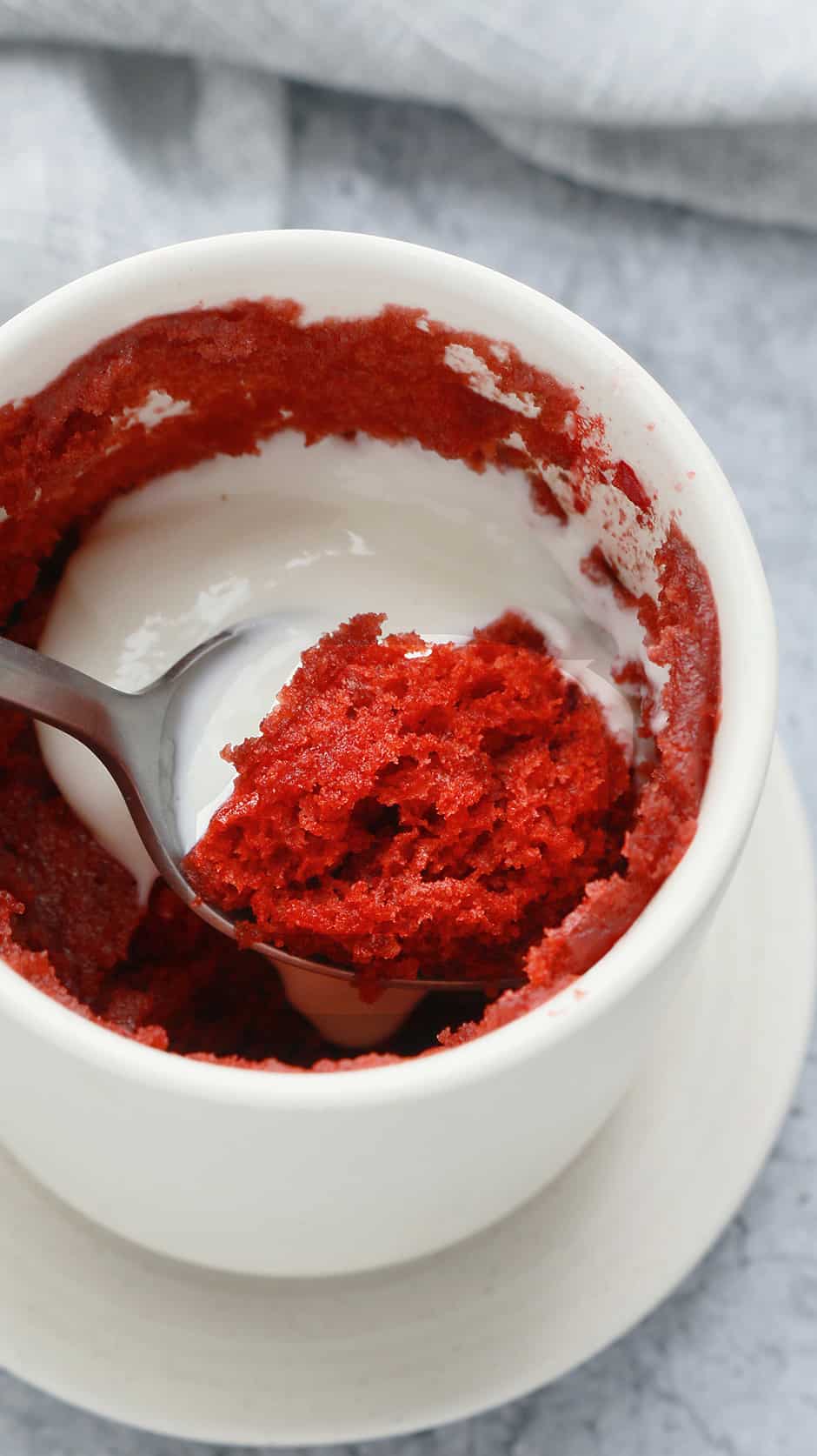 removing a spoon of red velvet cake topped with greek yogurt from a mug