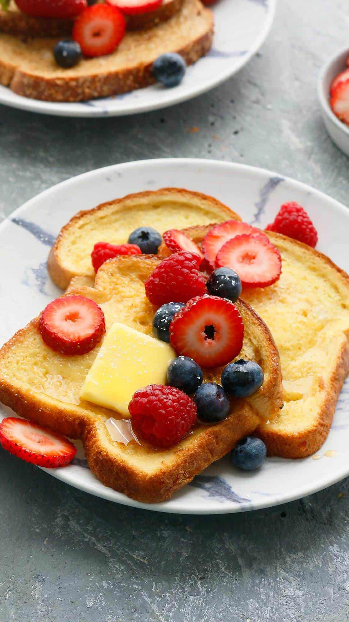 a plate with french toast topped with maple syrup and berries