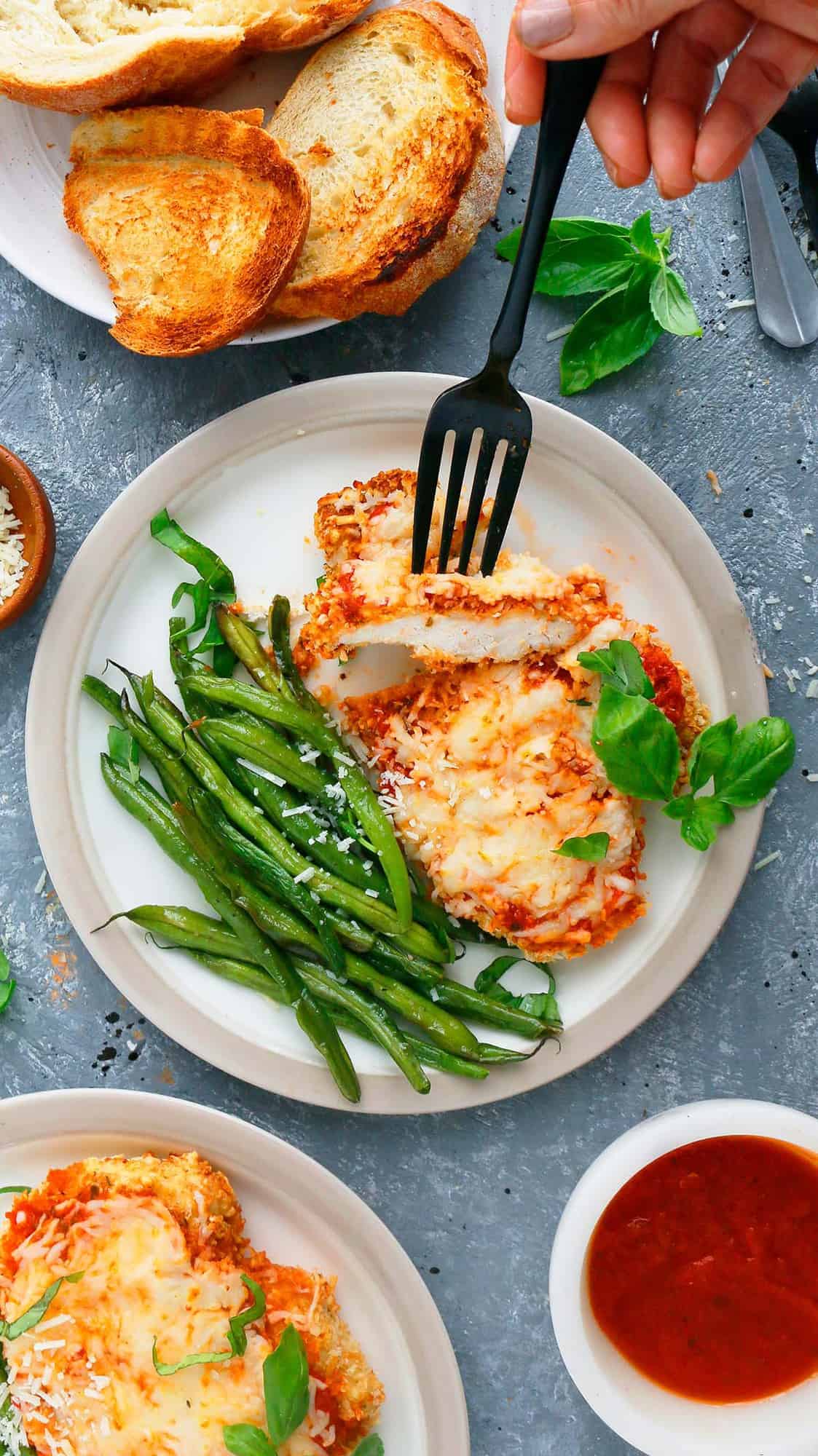 parmesan chicken made in air fryer served on white plates along with green beans