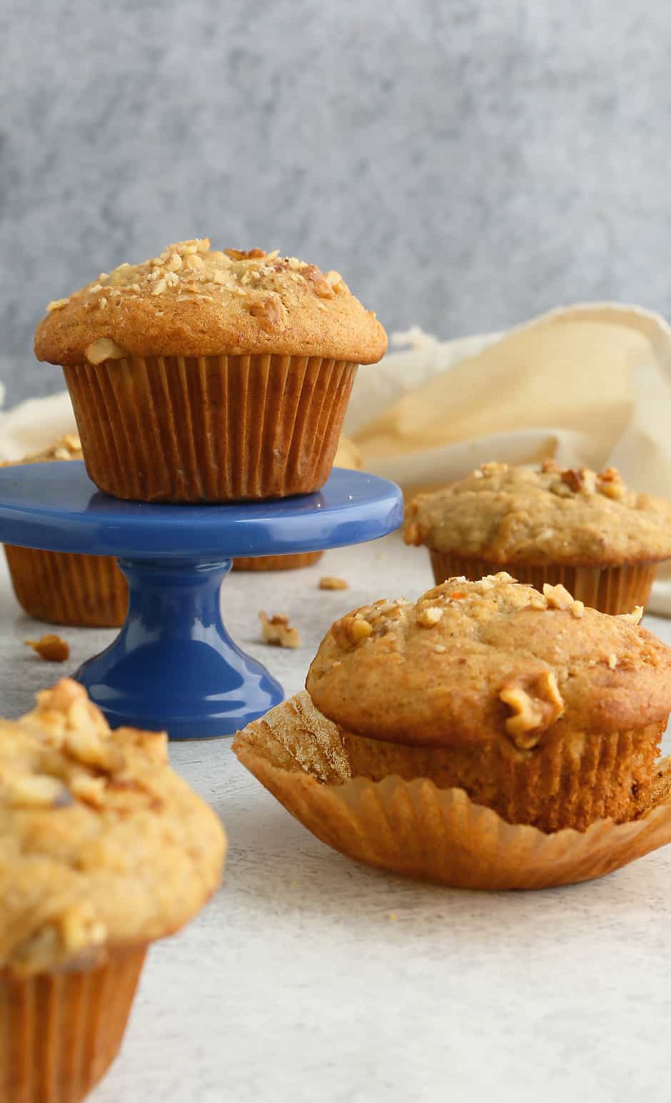 an eggless banana muffin placed on a blue cupcake stand along with more muffins