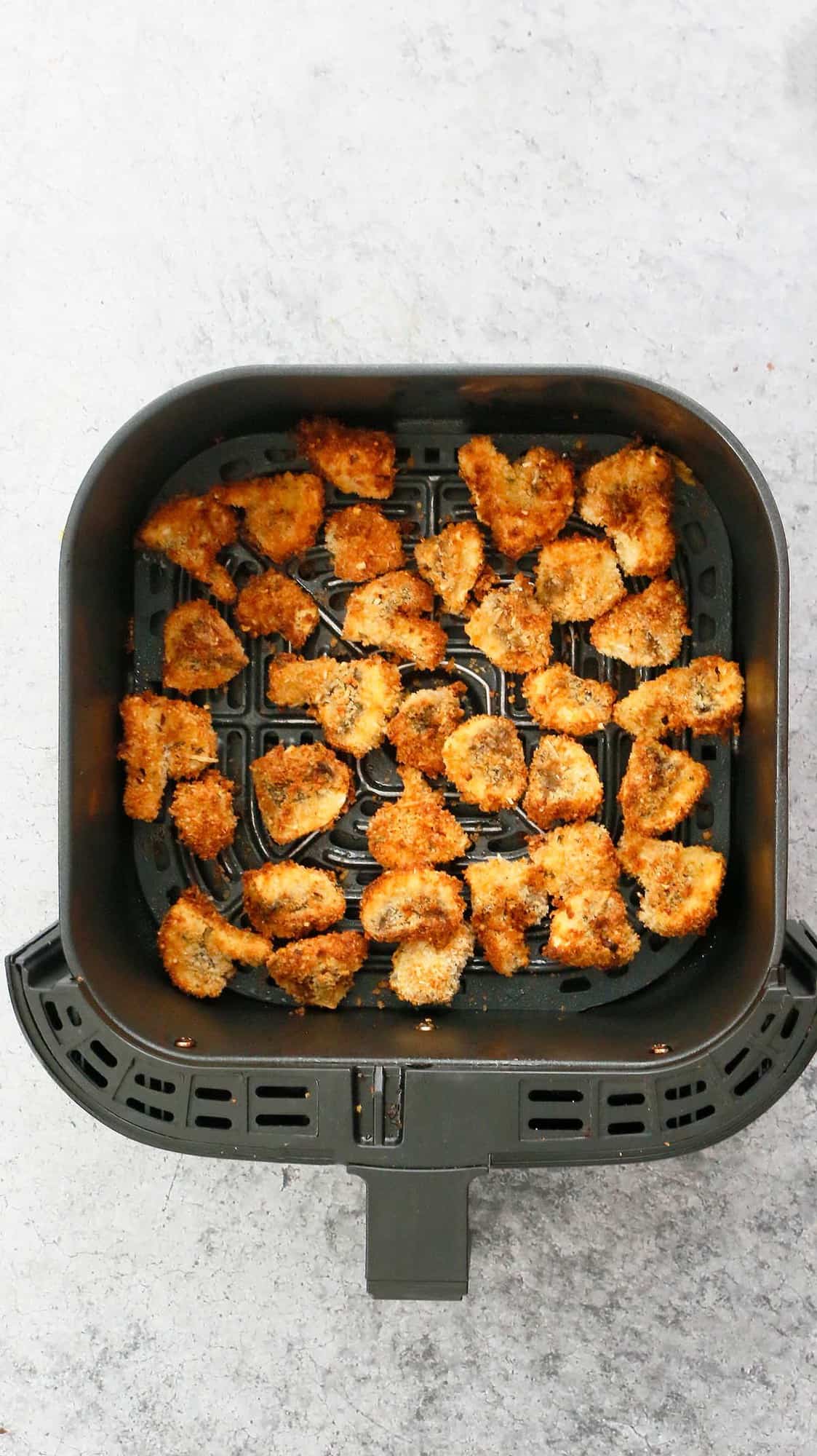 an air fryer basket with crispy breaded mushrooms