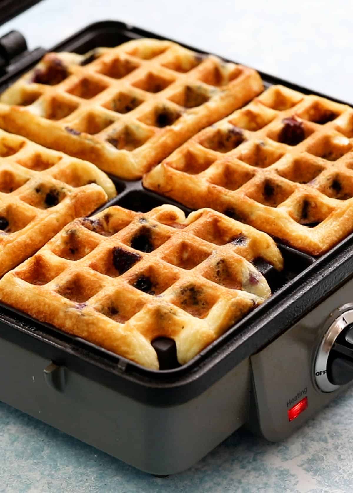 4 cooked waffles in a waffle maker.